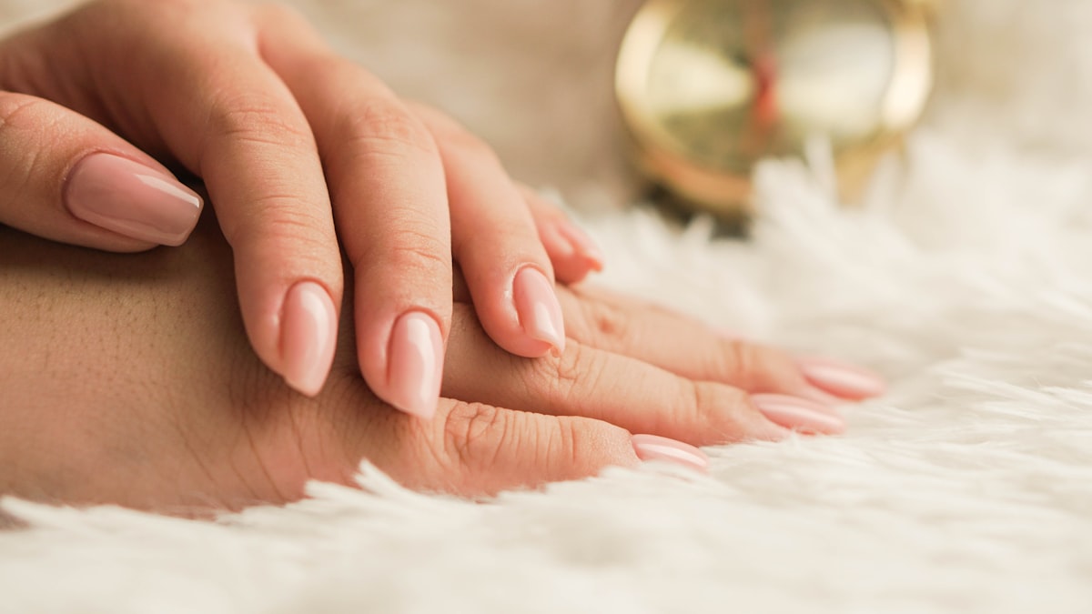 Glossy gel manicure in a soft nude shade.